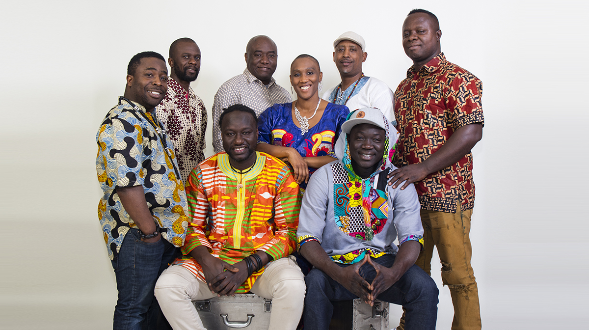 A portrait of seven men and one woman dressed in traditional African prints.